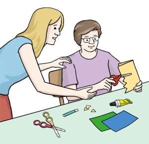 Auf dem Bild basteln zwei Personen gemeinsam mit Papier – eine davon wird dabei angeleitet. Das Bild zeigt eine Situation aus der Ergotherapie.