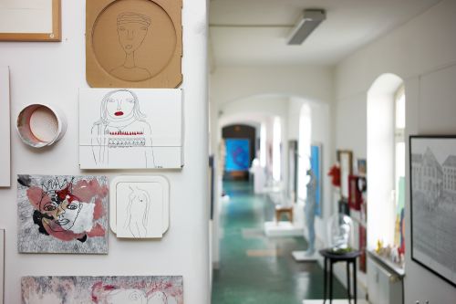 Das Bild zeigt einen hellen Ausstellungsflur im Atelier Blau, an dem zahlreiche Bilder und Skulpturen präsentiert werden.