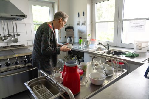 Das Bild zeigt eine Bewohnerin des Wohnhauses Samuelstraße beim Einräumen der Spülmaschine in der Gemeinschaftsküche.