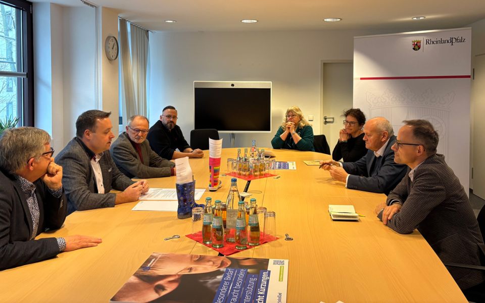 Das Bild zeigt eine Gruppe von Personen sitzen an einem großen Tisch und besprechen wichtige Themen.