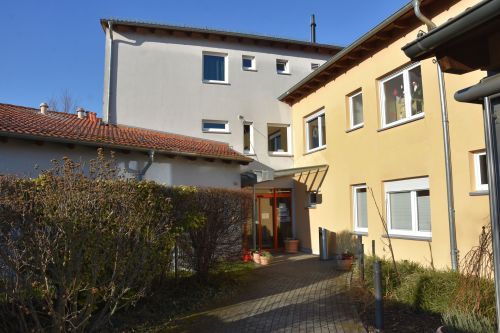 Das Bild zeigt den Eingang des Wohnhauses Klingweg mit seinem hellen Fassadenanstrich und einem begrünten Vorgarten.