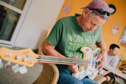Auf dem Bild sieht man einen Bewohner Gitarre spielen.