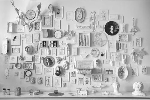 Das Bild zeigt eine Wand im Atelier Blau, die dicht mit vielfältigen Kunstwerken und Zeichnungen gestaltet ist.